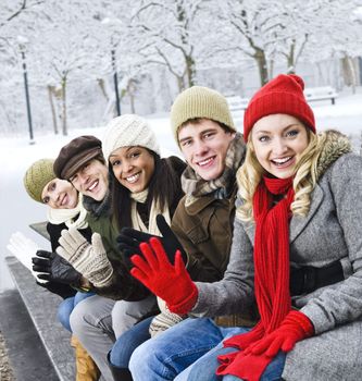 Group of diverse young friends waving hello outdoors in winter