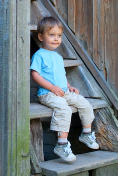 Cute 2 years old boy sitting on the the steps in the park