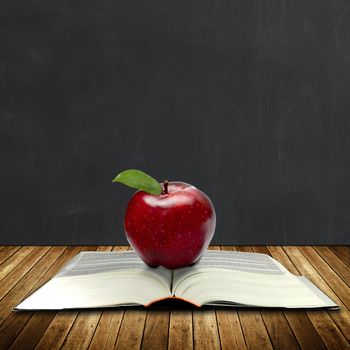 apple on a book with black board at the back