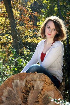 A pretty woman sitting on a fallen tree