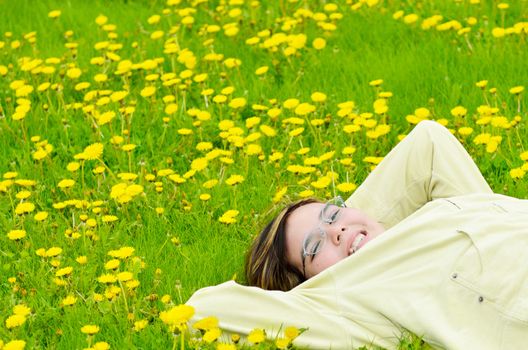 A young preteen girl is lying in the grass, relaxing in the sun.