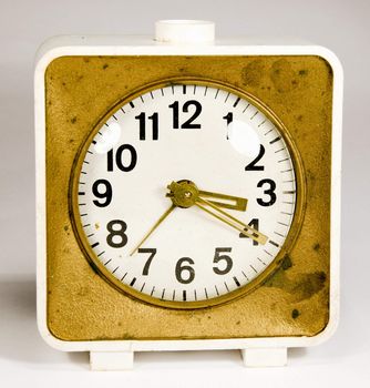 Ancient clock with three arrows showing 3:20. Old white gold alarm clock.