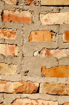 Fragment of old squared red brick wall with many cement on it.