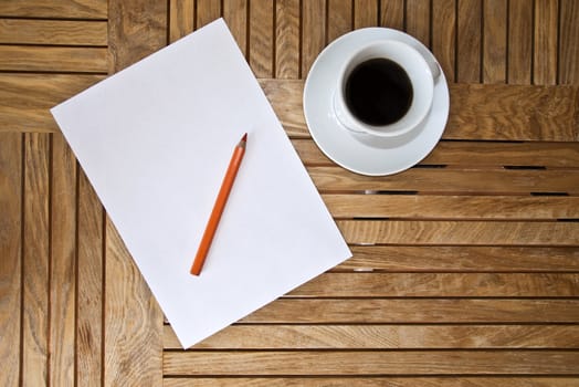 Paper blank Sheet, color pencil and a cup of coffee on a wooden table.