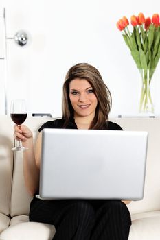 woman on sofa with computer and glass of wine