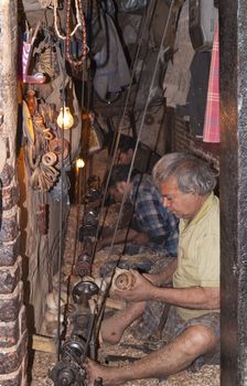 Men working in a sweat shop making wooden curtain rings on primitive lathes in a very small narrow windowless room in Old Delhi, India