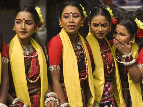 Group of teenage Indian dancers in traditional tribal outfit spot something of interest at the Sarujkund Craft Fair in Haryana near Delhi, India.