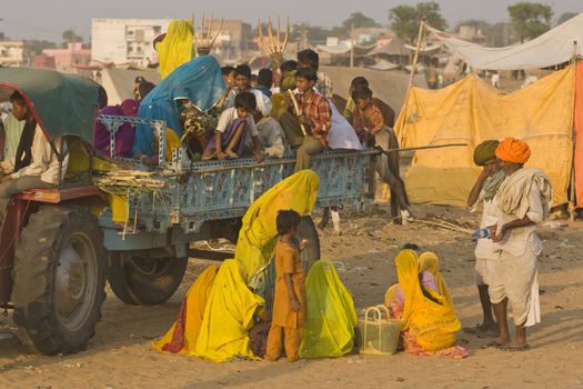 Group of people in traditional Indian clothing in the trailer of a farm tractor at the annual camel fair in Pushkar, Rajasthan, India.