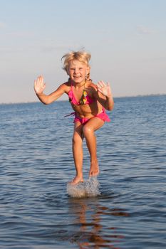 happy girl jumping in the water in the evening