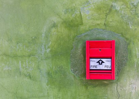 Red Fire alarm on green wall