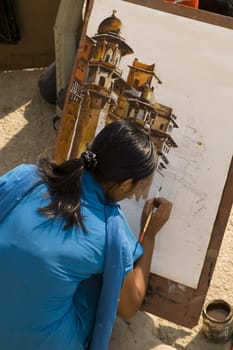 Lady in blue sari painting a picture on the ghats in Varanasi, India