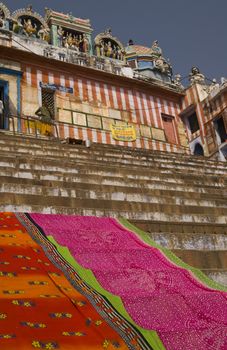 Colorful sari's drying on the ghats at Varanasi, India below a Hindu Temple