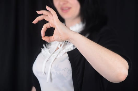 Woman at background indicating ok sign on a black background