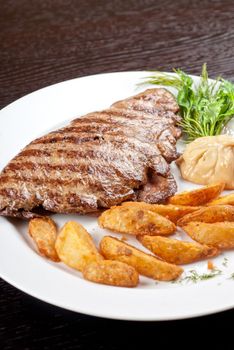 Juicy beef steak stuffed with beef tongue and cheese served with potatoes, greenery and sauce
