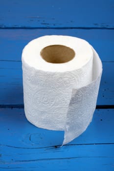 roll of white toilet paper over blue wooden table