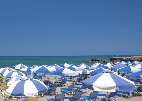 Blue and White Beach Umbrellas on a Beach in Greece under a blue summer sky