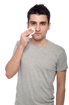 handsome young man cleaning face with cotton swab (isolated on white background)