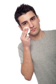 handsome young man cleaning face with cotton swab (isolated on white background)