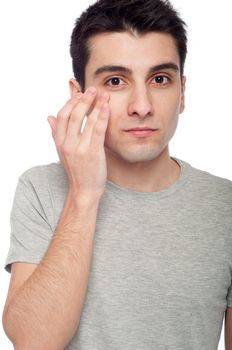 handsome young man applying eye cream for dark circles (isolated on white background)