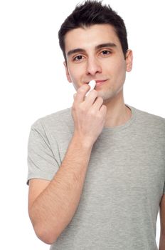 handsome young man applying lip balm (isolated on white background)