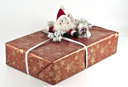 Red Christmas present with a santa doll and some jingle bells on top
