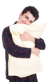 smiling young man in pajamas holding pillow isolated on white background