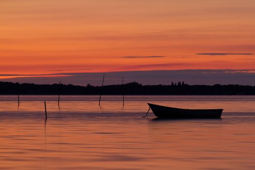 Scenic view of small fishing boat at sunset with cloudscape background.