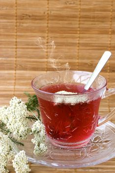 Achillea millefolium tea on wooden mat with fresh herbs