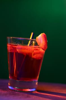 Strawberry drink photographed in a studio by using lighting color filters (Selective Focus, Focus on the front rim of the glass and the front of the strawberry slice on the rim)