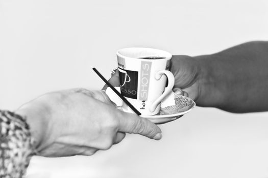 two hands exchanging a cup of coffee