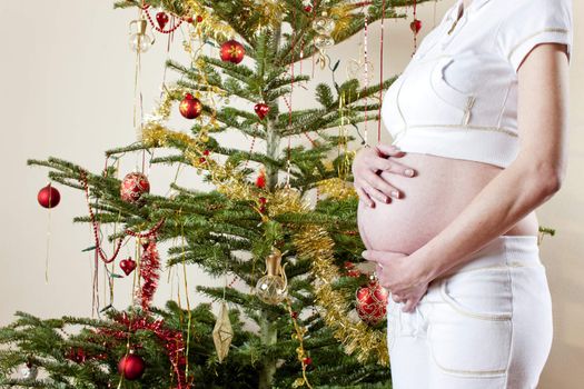 detail of pregnant woman standing by Christmas tree