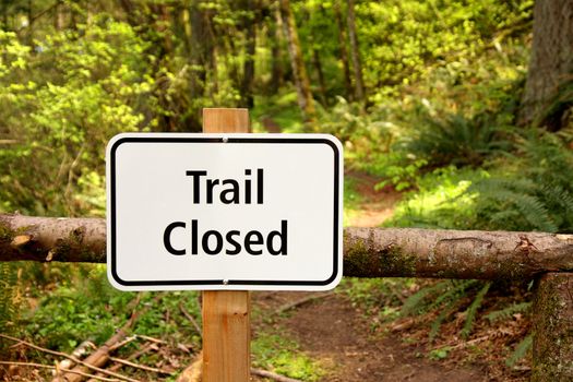 Trail closed sign along path in the woods