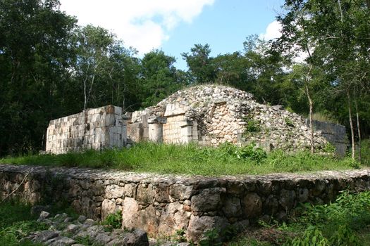 Maya ruins in green jungle over blue sky