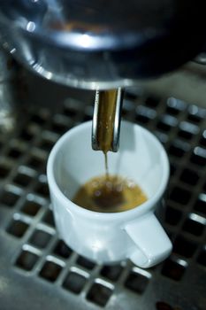 antique espresso machine filling a small caffe cup