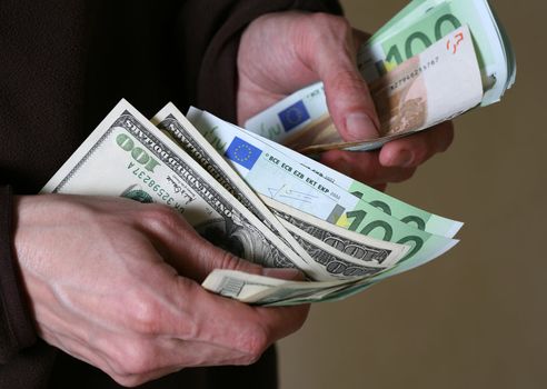 Man's hands hold Euro and dollars banknotes money