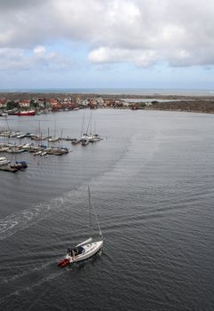 Yacht under Norwegian flag leaving the marina of Swedish fishermen village.