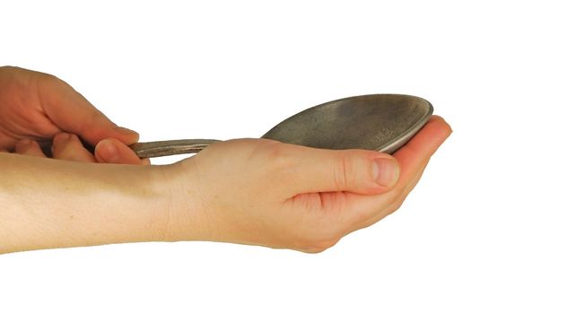 a womanish hand holds big spoon on a white background