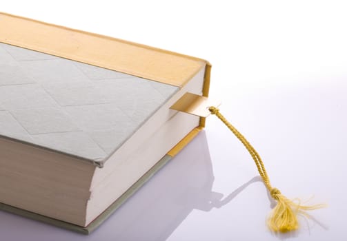 A book with a gold bookmark with a tassel on a background.