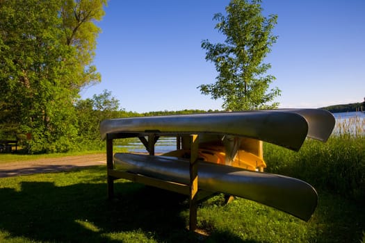 Canoes and kayaks on a platform resting by a lakeside.