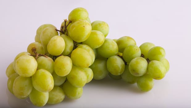 A green grape bunch on a white reflective background