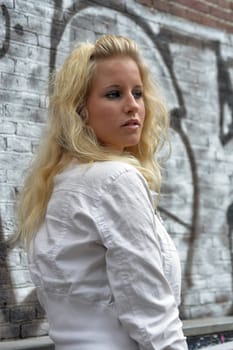 Attractive blonde standing against a brick wall with graffiti