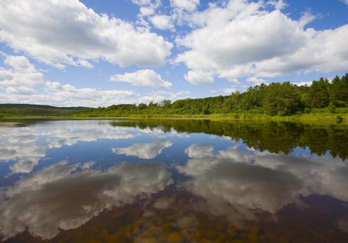 Mirror of clouds and forest  on the surface of a lake in the North Woods of Minnesota.