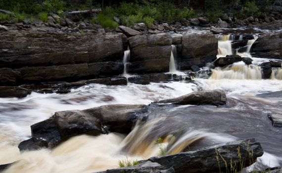 Water rushing down steps into the rapids of a raging river.