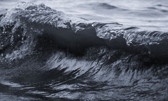 a detail of a wave breaking against the shore in a slight tint.