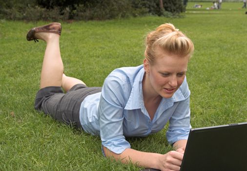 woman laying on the grass, working with laptop