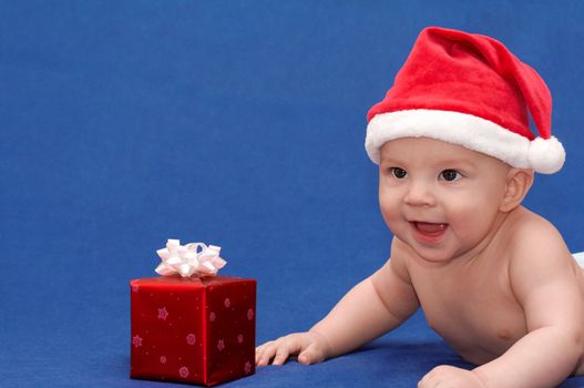 Smiling baby in santa's cap with gift