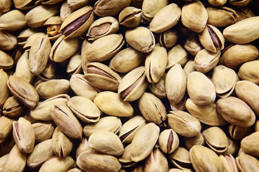 A pile of beautiful, tasty looking pistachio nuts still in their shells. Appetising nuts.