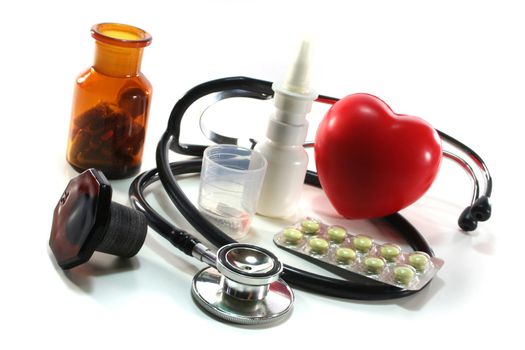 Stethoscope with heart and pills on a white background