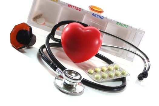 Stethoscope with heart and pills on a white background