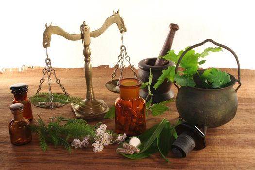 Pharmacists scale with mortar, old pot, apothecary jar and fresh herbs